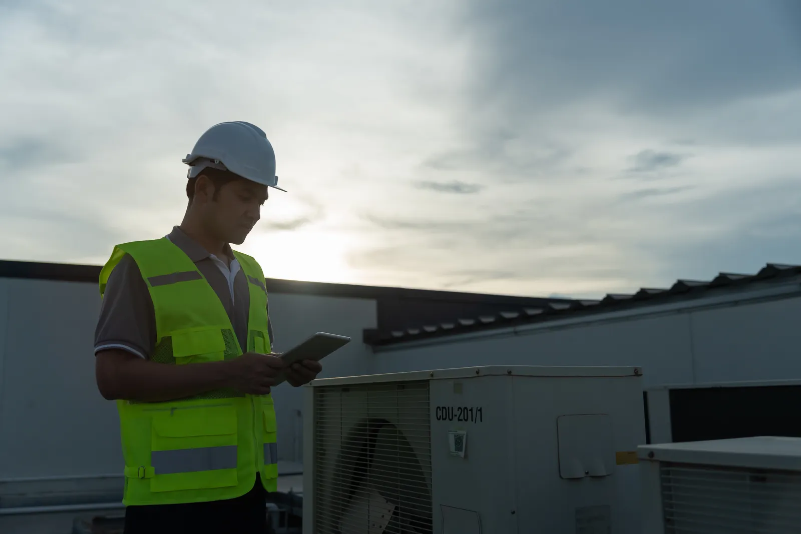 Roofing professional inspecting a roof at sunset